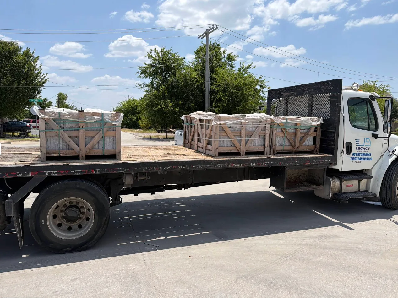 Flatbed truck loaded with crated pallets of stone leaving the yard